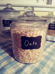 Oats in glass canister with chalkboard label that says oats