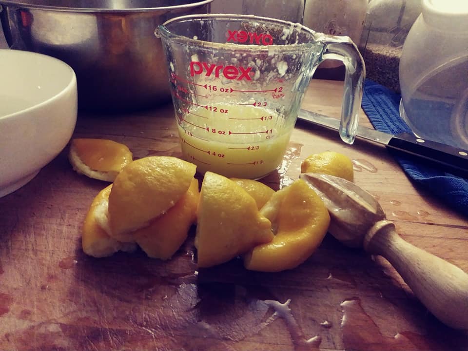 juicing lemons with a wooden reamer, juice in pyrex container