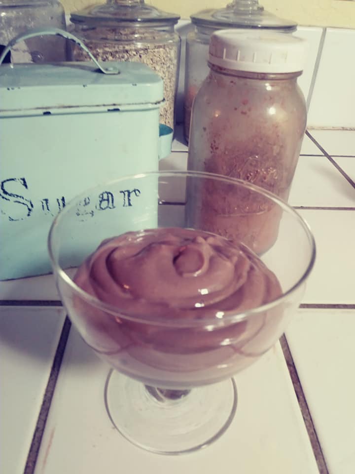 chocolate mousse next to blue suagr canister and mason jar with cocoa