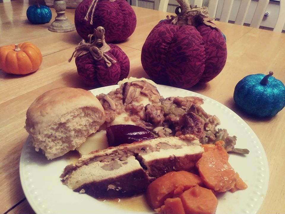 Thanksgiving plate of food with tofu turkey, rolls, cranberries, sweet potato dish, green bean casserole
