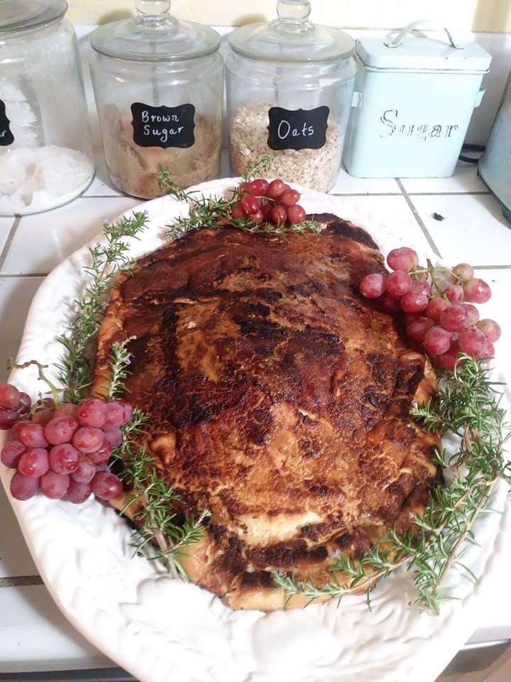 Tofu turkey on a white platter with grapes and rosemary