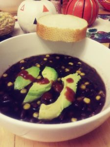 bowl of vegan black bean soup with avocado slices