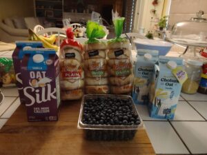 Three packs of Safeway bagels, Silk and Chobani Oatmilk and blueberries