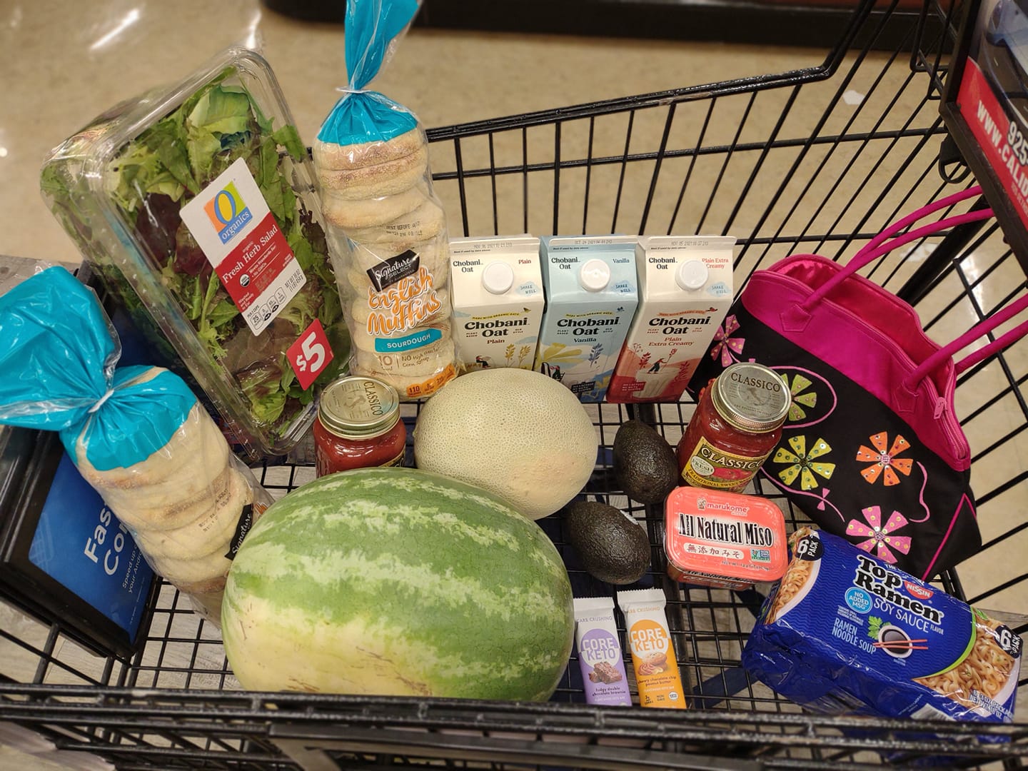 My cart full of vegan groceries, includes watermelon, cantaloupe, Chobani Oatmilk, Core Keto Bars, sourdough English Muffins, Classico pasta sauce, salad pack, soy sauce Top Ramen, avocados
