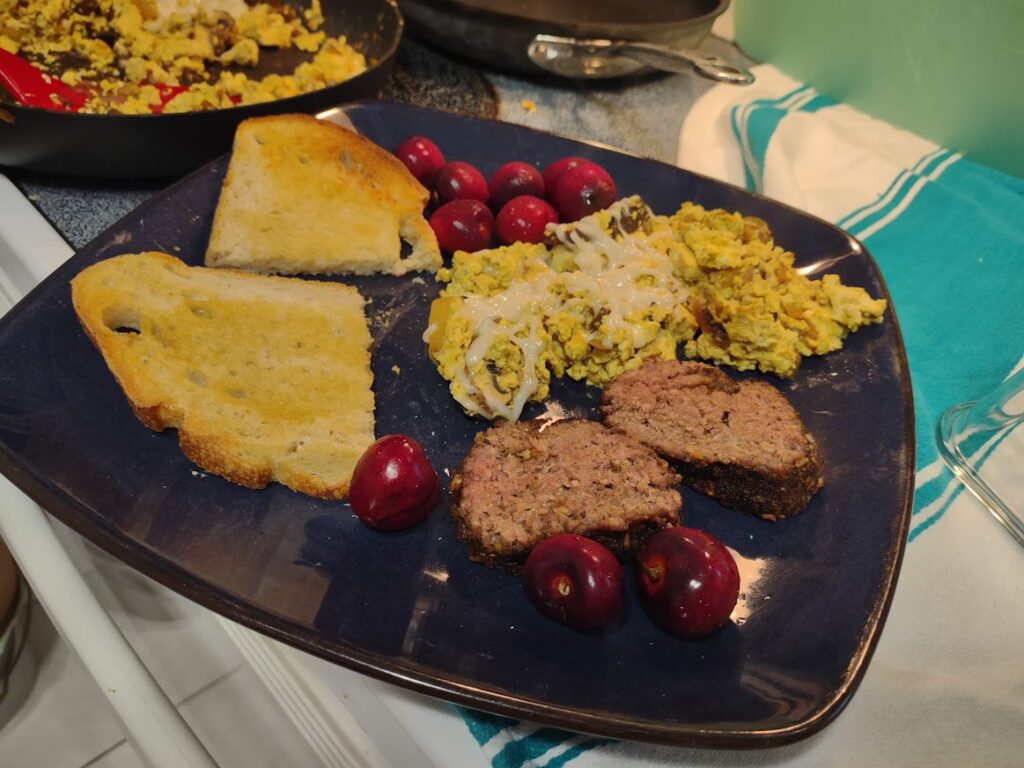 plate with vegan steak, tofu scramble, cherries and sourdough bread