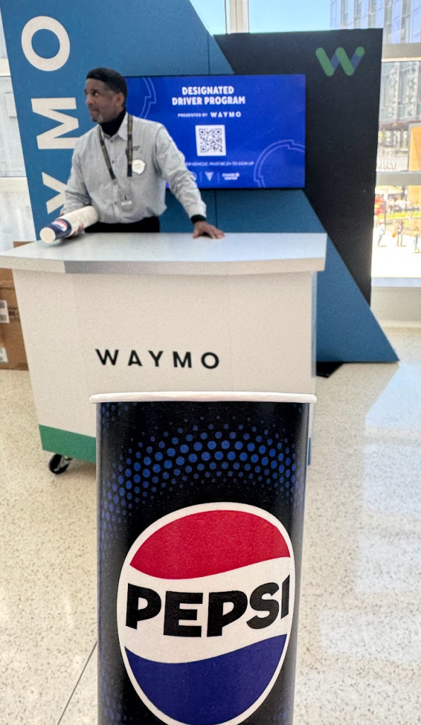 Waymo booth with man and Pepsi cup